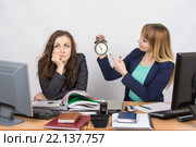 Офисные сотрудницы в конце рабочего дня, одна с улыбкой указывает на часы, другая задумчиво подпирает голову. Стоковое фото, фотограф Иванов Алексей / Фотобанк Лори