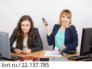 Радостная девушка в офисе с телефоном в руке рядом с недовольной коллегой. Стоковое фото, фотограф Иванов Алексей / Фотобанк Лори