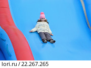 Ребёнок девочка катается с улыбкой на надувной разноцветной горке на празднике Масленицы на Московской площади в Санкт-Петербурге 2016-03-13. Редакционное фото, фотограф Максим Мицун / Фотобанк Лори