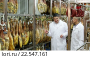 Technologist with butcher checking drying wurst and jamon at factory. Стоковое видео, видеограф Яков Филимонов / Фотобанк Лори