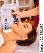 Relaxed young woman receiving electric facial massage. Стоковое фото, фотограф Gennadiy Poznyakov / Фотобанк Лори