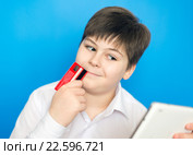 Мальчик-подросток с планшетом и банковской картой совершает покупку через интернет. Стоковое фото, фотограф Володина Ольга / Фотобанк Лори