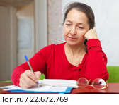 serious mature woman fills in documents. Стоковое фото, фотограф Яков Филимонов / Фотобанк Лори