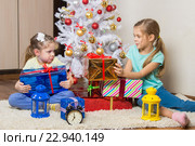 Две девочки делят подаренные на Новый год подарки у елки. Стоковое фото, фотограф Иванов Алексей / Фотобанк Лори
