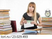 Расстроенная девушка студентка кладет деньги в конверт для взятки преподавателю на экзамене. Стоковое фото, фотограф Иванов Алексей / Фотобанк Лори