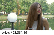 Девушка пишет смс на фоне города, видит знакомого человека и машет ему рукой. Стоковое видео, видеограф Игорь Усачев / Фотобанк Лори