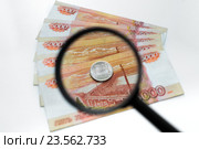 Монета достоинством один рубль на фоне купюр в пять тысяч  лежит под увеличительным стеклом. Стоковое фото, фотограф Виталий Антонов / Фотобанк Лори