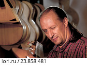 Гитарный мастер проверяет гриф гитары. luthier. Стоковое фото, фотограф Аlexander Reshetnik / Фотобанк Лори