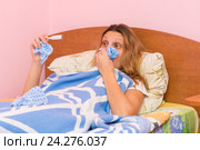 Заболевшая девушка сморкается в носовой платок и смотрит на градусник. Стоковое фото, фотограф Иванов Алексей / Фотобанк Лори