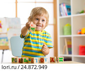 Little preschooler child boy playing with toy cubes and memorizing letters. Early education concept. Стоковое фото, фотограф Оксана Кузьмина / Фотобанк Лори