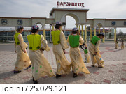 Девушки в национальных костюмах проходят мимо входа на стадион в городе Худжанд в Республике Таджикистан (2015 год). Редакционное фото, фотограф Николай Винокуров / Фотобанк Лори