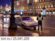 Сотрудник ДПС ГИБДД дежурит на улице города вечером рядом с автомобилем со спецсигналами (2014 год). Редакционное фото, фотограф Иван Козлович / Фотобанк Лори