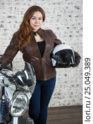 Woman a biker holding hand a white open helmet and standing behind the motorbike. Стоковое фото, фотограф Кекяляйнен Андрей / Фотобанк Лори