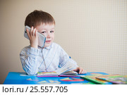 Little boy sitting at desk and talking on the phone. Стоковое фото, фотограф Happy Letters / Фотобанк Лори