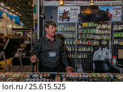 Moscow, Russia - February 25, 2017: Seller of fishing gear on the background with wobblers waiting for customers. Редакционное фото, фотограф Андрей Копылов / Фотобанк Лори