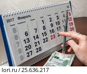 Шариковая ручка в руке и деньги на фоне календаря (2017 год). Редакционное фото, фотограф Игорь Низов / Фотобанк Лори