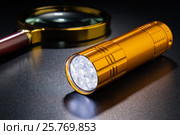 Luminous flashlight on a dark surface. Magnifier in the background. Стоковое фото, фотограф Alexander / Фотобанк Лори