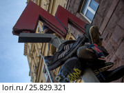 Старые кроссовки висят на букве М у входа в метро Тверская в городе Москве после несанкционированного митинга против коррупции, Россия (2017 год). Редакционное фото, фотограф Николай Винокуров / Фотобанк Лори