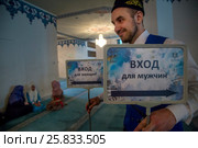 Волонтер несет таблички для раздельного входа в мечеть в зале Московской соборной мечети во время Фестиваля Корана, Россия (2017 год). Редакционное фото, фотограф Николай Винокуров / Фотобанк Лори