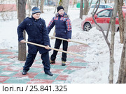 Two boys clean artificial green-red covering of playground with snow shovels. Стоковое фото, фотограф Losevsky Pavel / Фотобанк Лори