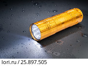 Pocket LED flashlight in the rain on a dark surface. Water drops. Стоковое фото, фотограф Alexander / Фотобанк Лори