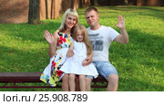 Pregnant mother, father, little daughter wave hands on bench in summer park. Стоковое видео, видеограф Светлана Додух / Фотобанк Лори