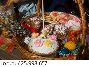Корзинка с пасхальной выпечкой, веточками вербы и крашенными яйцами на столе у православного храма во время освящения в Великую субботу в городе Москве, Россия (2017 год). Редакционное фото, фотограф Николай Винокуров / Фотобанк Лори
