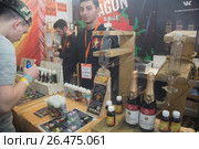 Продавцы за прилавком в магазине курительных смесей продают разные сорта жидкостей для электронных сигарет на выставке Vape Show в городе Москве,  Россия (2017 год). Редакционное фото, фотограф Николай Винокуров / Фотобанк Лори