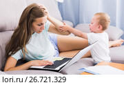 Perplexed mom is having issue with work while child crying. Стоковое фото, фотограф Яков Филимонов / Фотобанк Лори