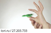 Hands of a teenage girl spin a green fidget spinner on white background stock footage video. Стоковое видео, видеограф Юлия Машкова / Фотобанк Лори