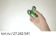 Hands of a teenage girl spin a green fidget spinner on white background stock footage video. Стоковое видео, видеограф Юлия Машкова / Фотобанк Лори