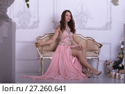 Девушка в длинном розовом платье сидит на софе. Стоковое фото, фотограф Литвяк Игорь / Фотобанк Лори