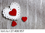 День святого Валентина, свадьба, любовь. Белые ажурные и красные яркие деревянные сердца на серебристом сером фоне с пустым местом для написания текста поздравления или приглашения. Valentine's Day, wedding, love. White openwork and red bright wooden hearts on a silvery gray background with an empty space for writing congratulations or invitations. Стоковое фото, фотограф Светлана Евграфова / Фотобанк Лори
