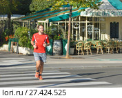 PARIS, FRANCE - OCTOBER 16, 2016: Amateur runner runs near a cafe on the street of Paris. Редакционное фото, фотограф Irina Kuchugurina/Gaudy / Фотобанк Лори