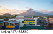 LEGAZPI, PHILIPPINES - JANUARY 5, 2018: - Mount Mayon volcano looms over the city as daily life goes on. Редакционное фото, фотограф Mikhail Davidovich / Фотобанк Лори