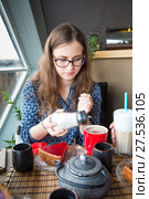 Young brown-hair woman pours sugar into a her cup. Стоковое фото, фотограф Сергей Дубров / Фотобанк Лори