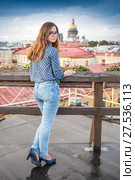 Leggy long-hair girl wearing blue jeans and blouse stands on the roof of the building in centre of Saint-Petersburg (2017 год). Стоковое фото, фотограф Сергей Дубров / Фотобанк Лори