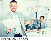 Happy entrepreneur with papers standing in office. Стоковое фото, фотограф Яков Филимонов / Фотобанк Лори