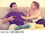 Woman trying to take away TV remote from boyfriend. Стоковое фото, фотограф Яков Филимонов / Фотобанк Лори