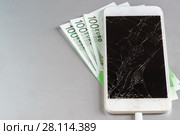 Смартфон с разбитым дисплеем и триста евро на оплату ремонта на сером столе. Стоковое фото, фотограф Наталья Гармашева / Фотобанк Лори