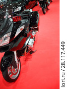 Black shiny bike for cortege is on red carpet in exhibition hall near other cars, bikes. Стоковое фото, фотограф Losevsky Pavel / Фотобанк Лори