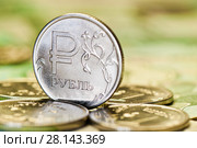Деньги. Один российский рубль крупным планом среди других монет на фоне однотысячных банкнот. Стоковое фото, фотограф E. O. / Фотобанк Лори
