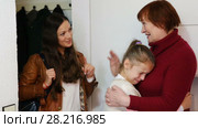 Smiling young mother leaving daughter in tears with grandma at home, saying goodbye. Стоковое видео, видеограф Яков Филимонов / Фотобанк Лори