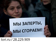 Женщина держит плакат с надписью "Мы заперты, мы сгораем!" во время траурной акции на Пушкинской площади города Москвы в память о погибших при пожаре в кемеровском торговом центре "Зимняя вишня", 27 марта 2018. Редакционное фото, фотограф Николай Винокуров / Фотобанк Лори