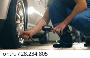 Auto mechanic pumps wheel of a car. Стоковое видео, видеограф Илья Шаматура / Фотобанк Лори