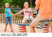 children are teetering on the swing in the playground. Стоковое фото, фотограф Яков Филимонов / Фотобанк Лори