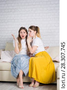 Two young girls are sitting on the couch. Стоковое фото, фотограф Типляшина Евгения / Фотобанк Лори