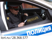 A Russian policeman cuts off a "police" badge from bulletproof vest (2012 год). Редакционное фото, фотограф Александр Клёнов / Фотобанк Лори