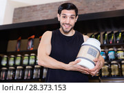 Athletic man seller demostration sport nutrition products in shop. Стоковое фото, фотограф Яков Филимонов / Фотобанк Лори