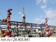 Россия, Тюменская область, Уватский район; Усть-Тегусское нефтяное месторождение; Кустовая площадка №1, задвижки с измерительными приборами на фоне буровой вышки. Стоковое фото, фотограф Александр Циликин / Фотобанк Лори